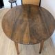 Antique wooden folding table with a patina and brass wheels.