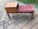 Mid-century teak telephone bench with bright pink tufted seat and side table.