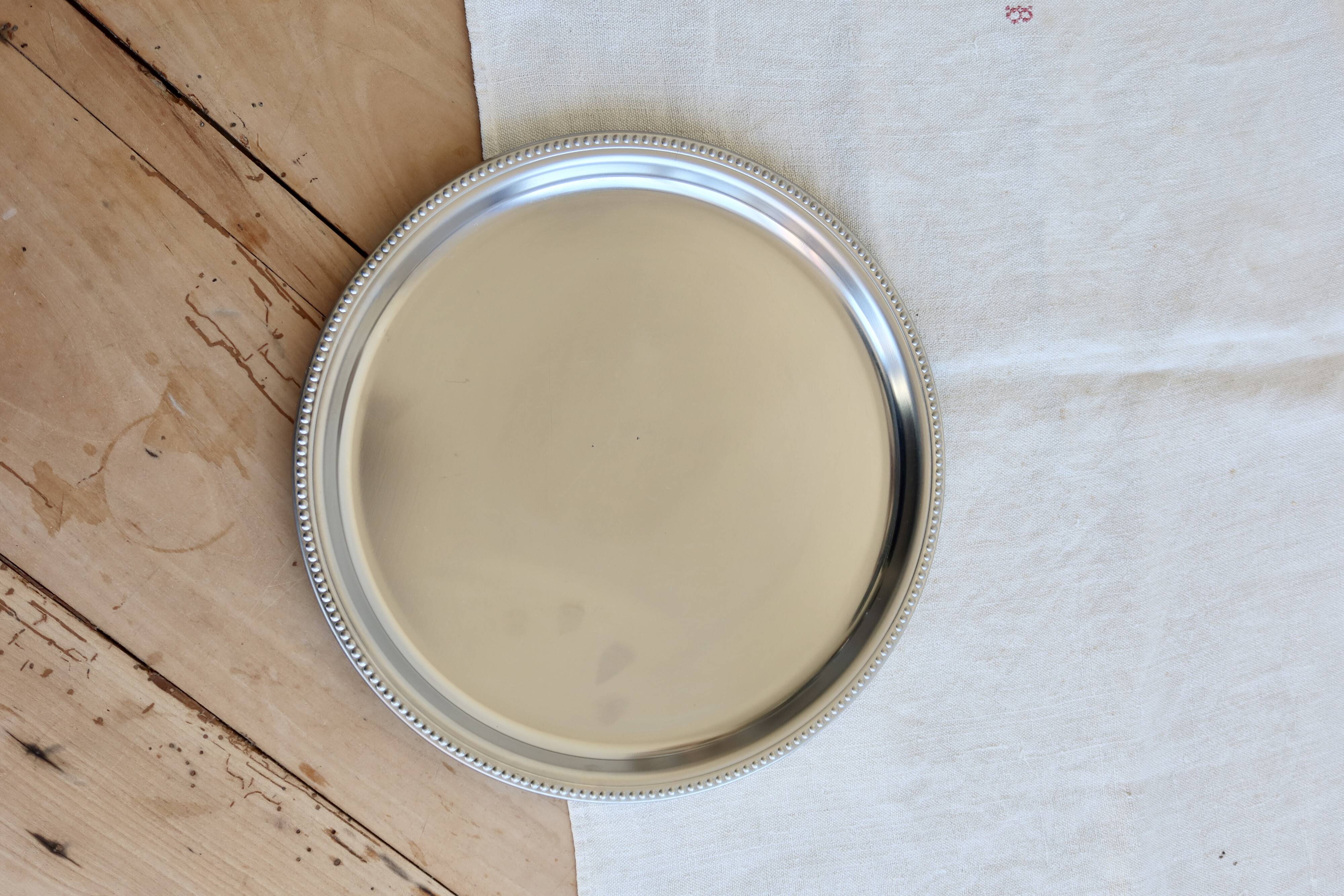 Vintage round metal plate with silver trim and beads.