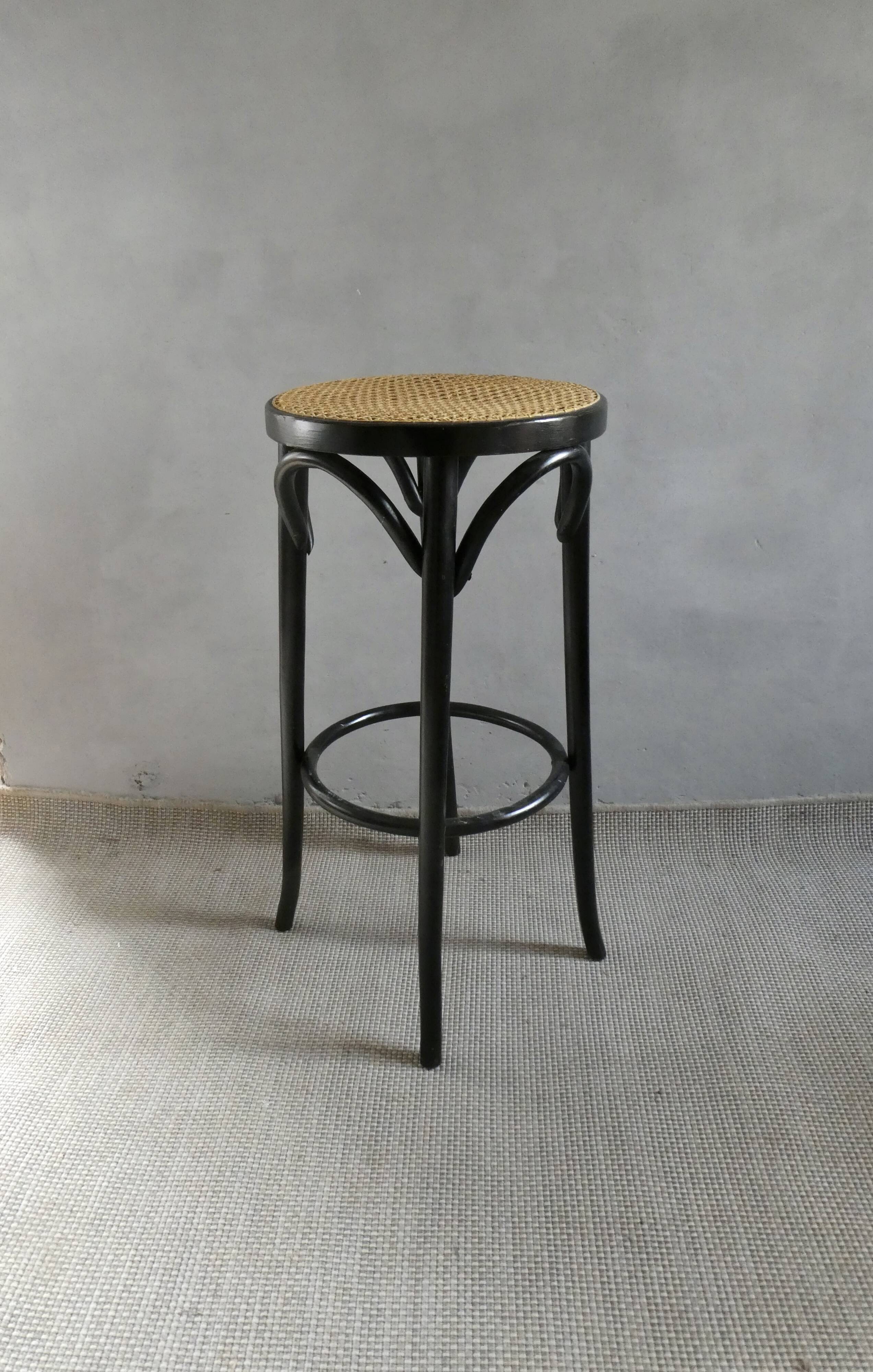 Curved wooden bar stool with a caned seat.