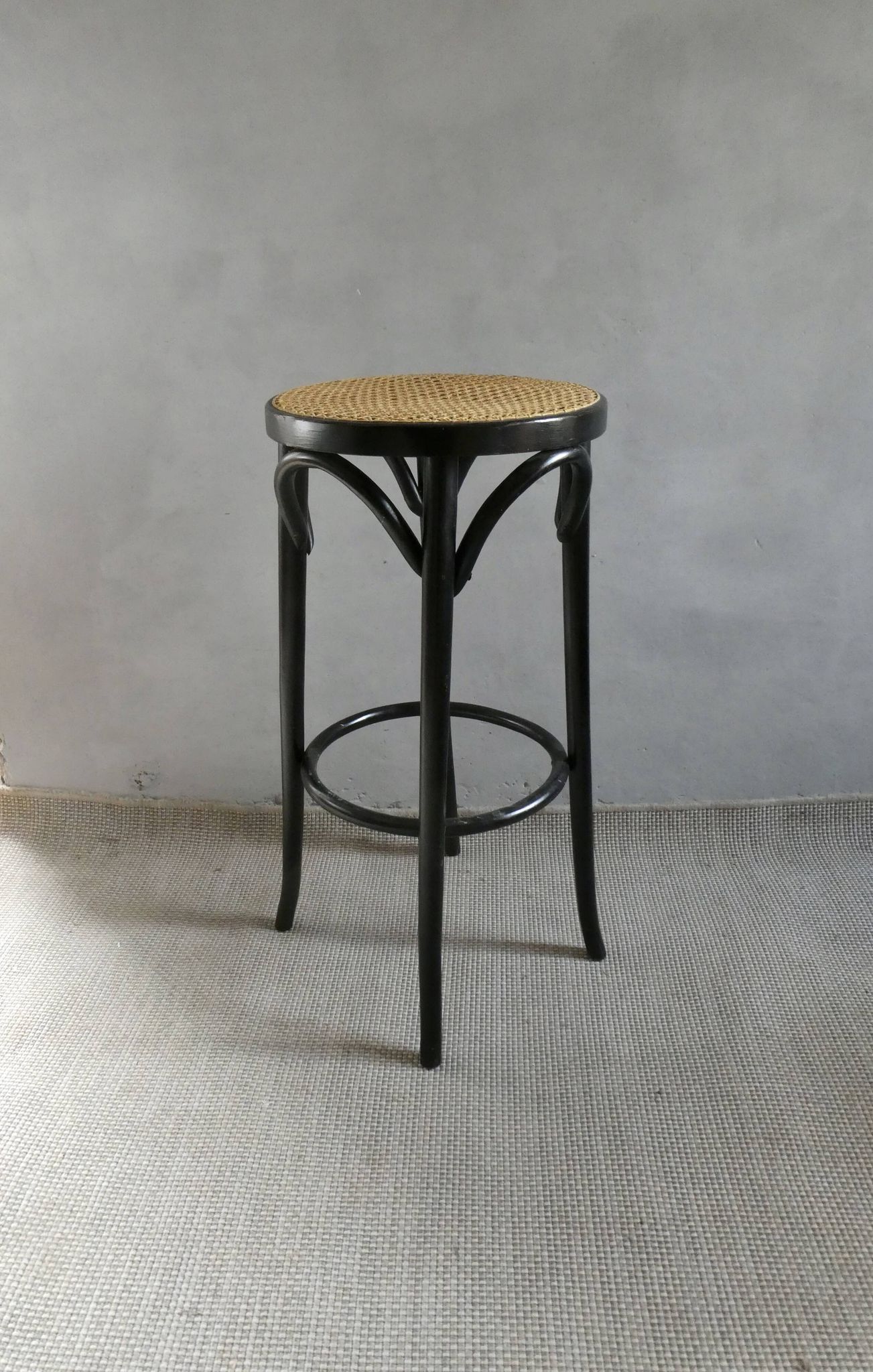 Curved wooden bar stool with a caned seat.