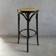 Curved wooden bar stool with a caned seat.