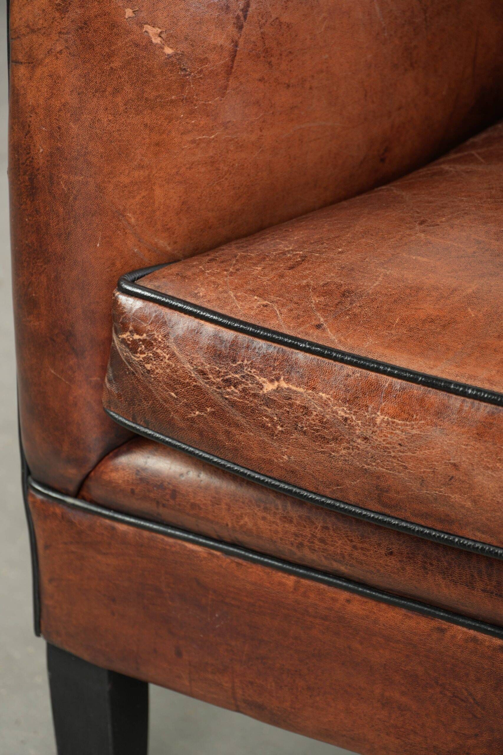 Fauteuil en peau de mouton confortable au design unique, fini avec un passepoil noir.