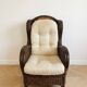 Vintage armchair in rattan and wicker with beige cushion.