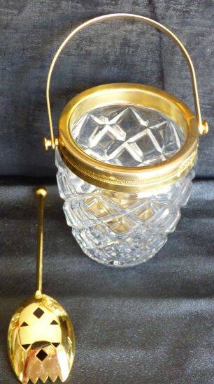 Glass and gold metal ice bucket with its gold metal spoon.