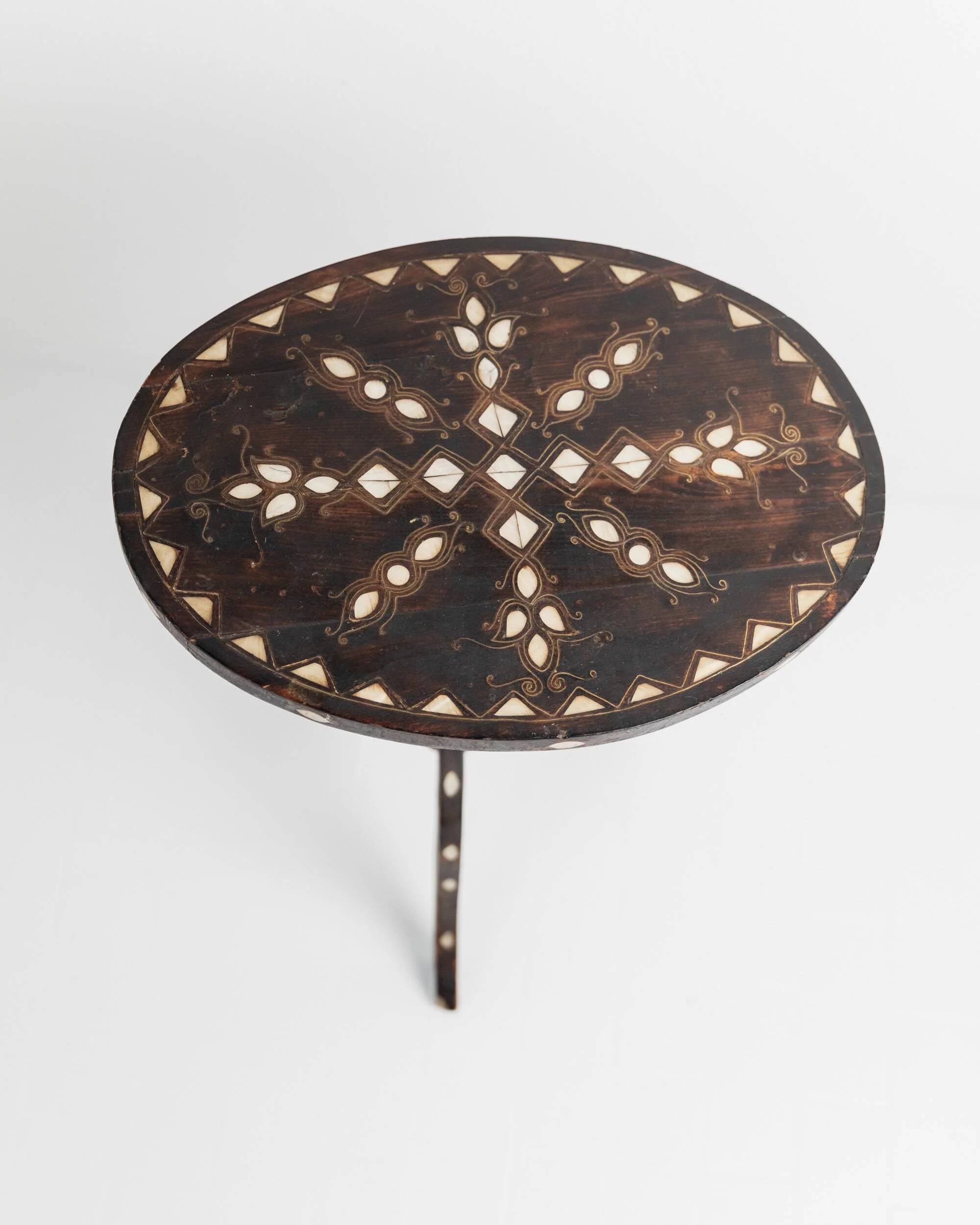 Vintage side table from the early 19th century, dark wood with mother-of-pearl inlays, oval shape with three legs, ethnic style.