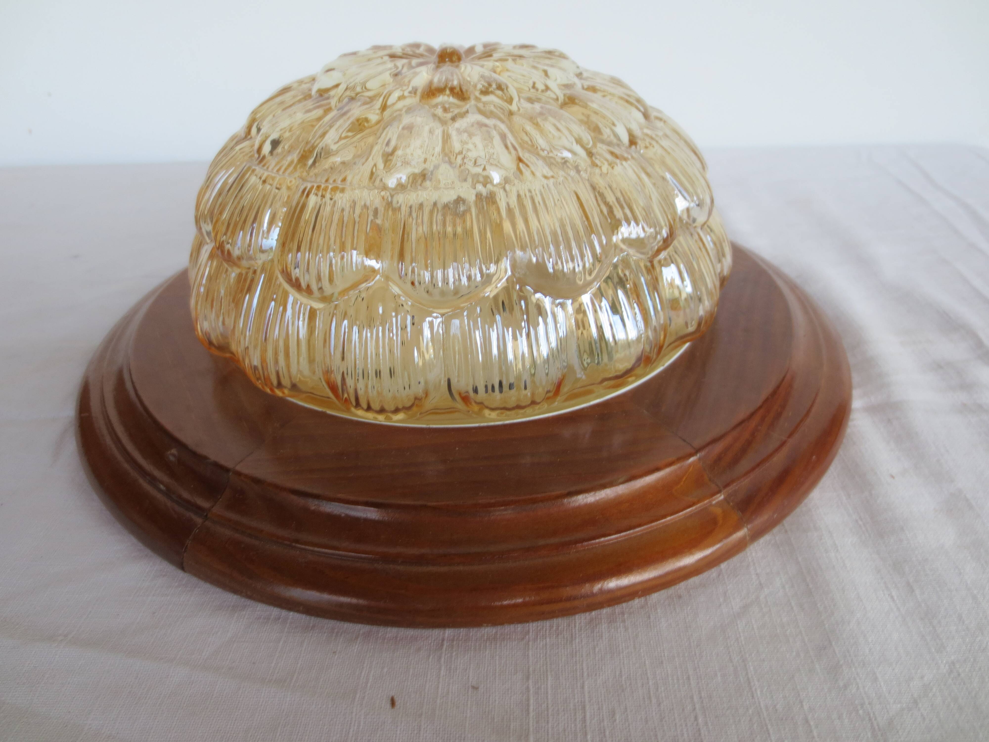 ceiling light with amber glass globe, on a round light wood base