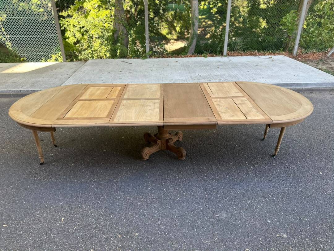 Round dining table with a central pedestal, stripped raw oak, 4 extensions, 19th century.
