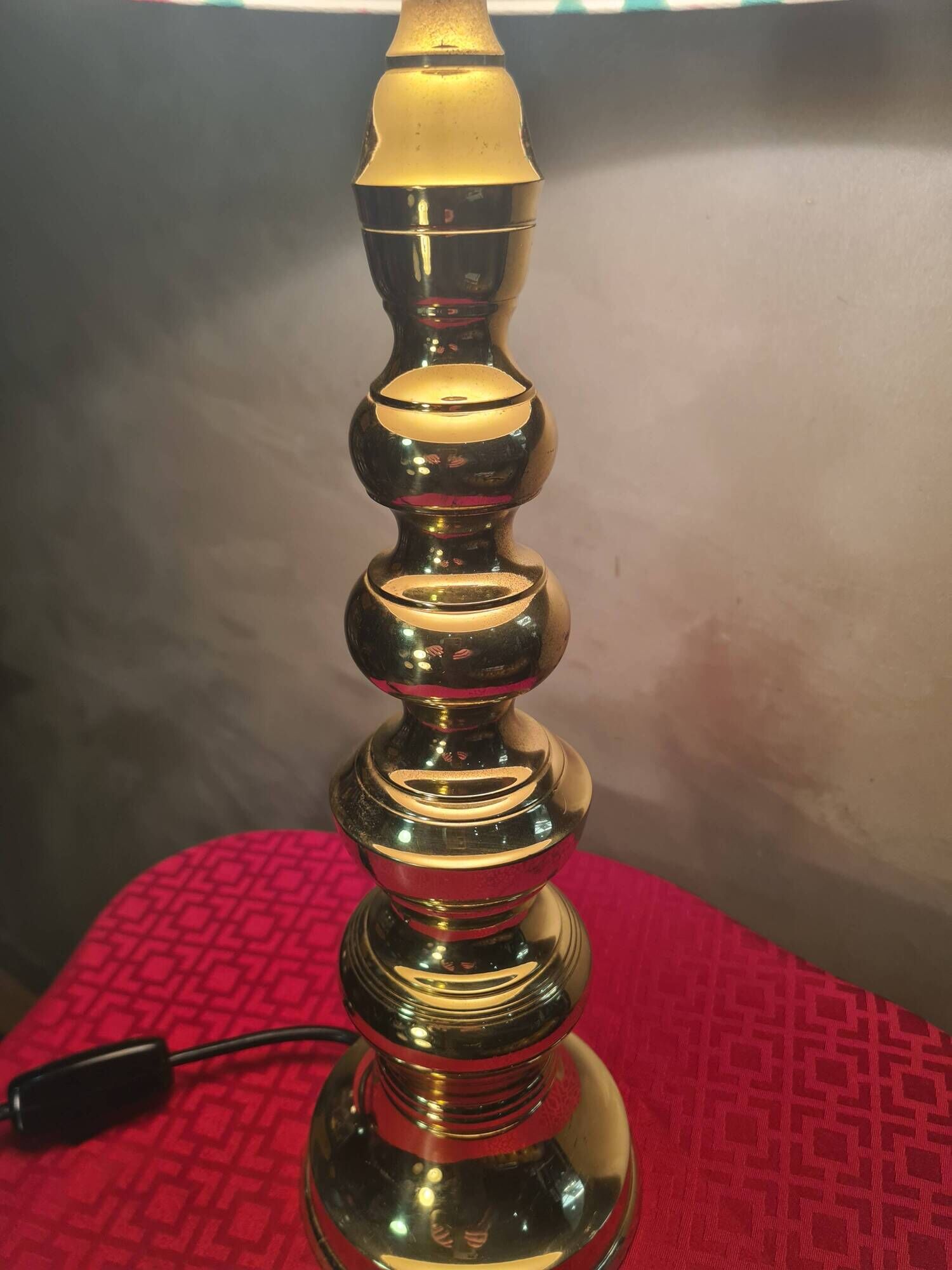 This elegant table lamp features a sculptural base in shiny gold brass.