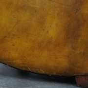 Comfortable large yellow English-style leather armchair with a fine finish and decorative nails