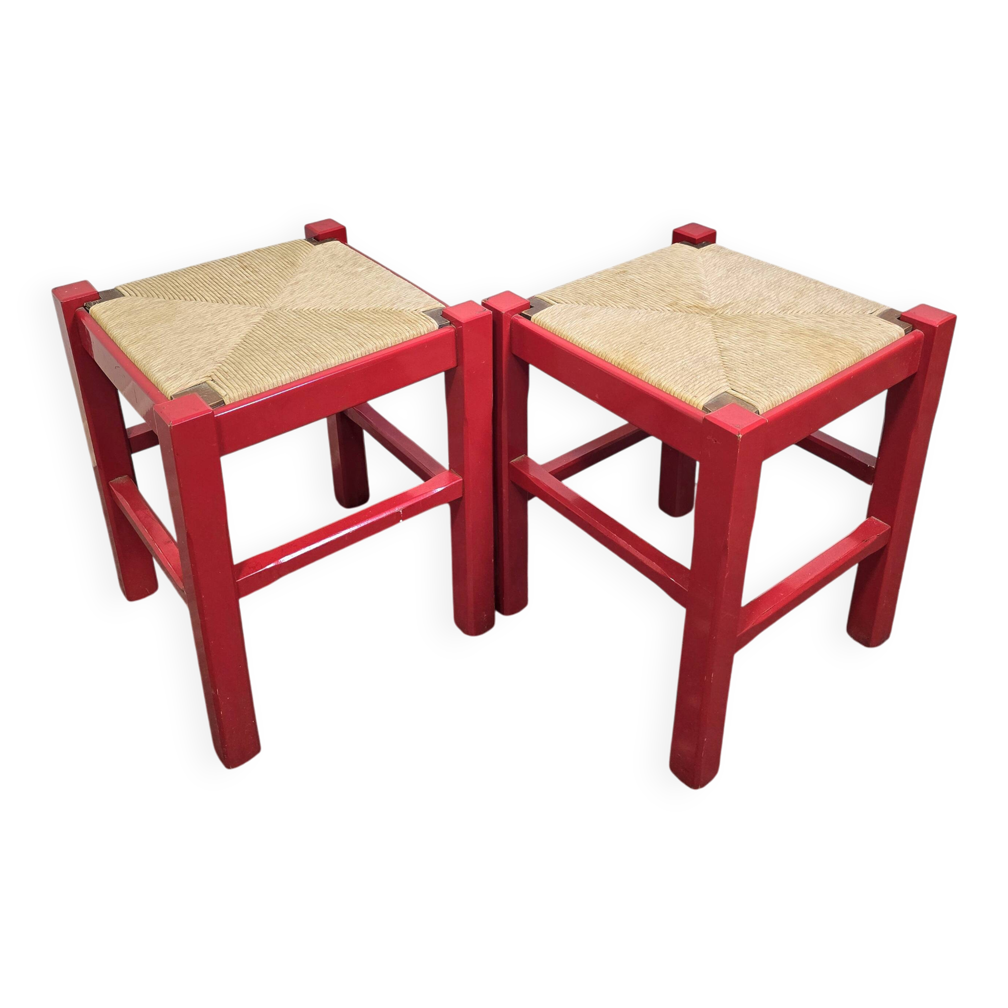 Red wooden stool with a woven straw seat.