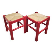 Red wooden stool with a woven straw seat.