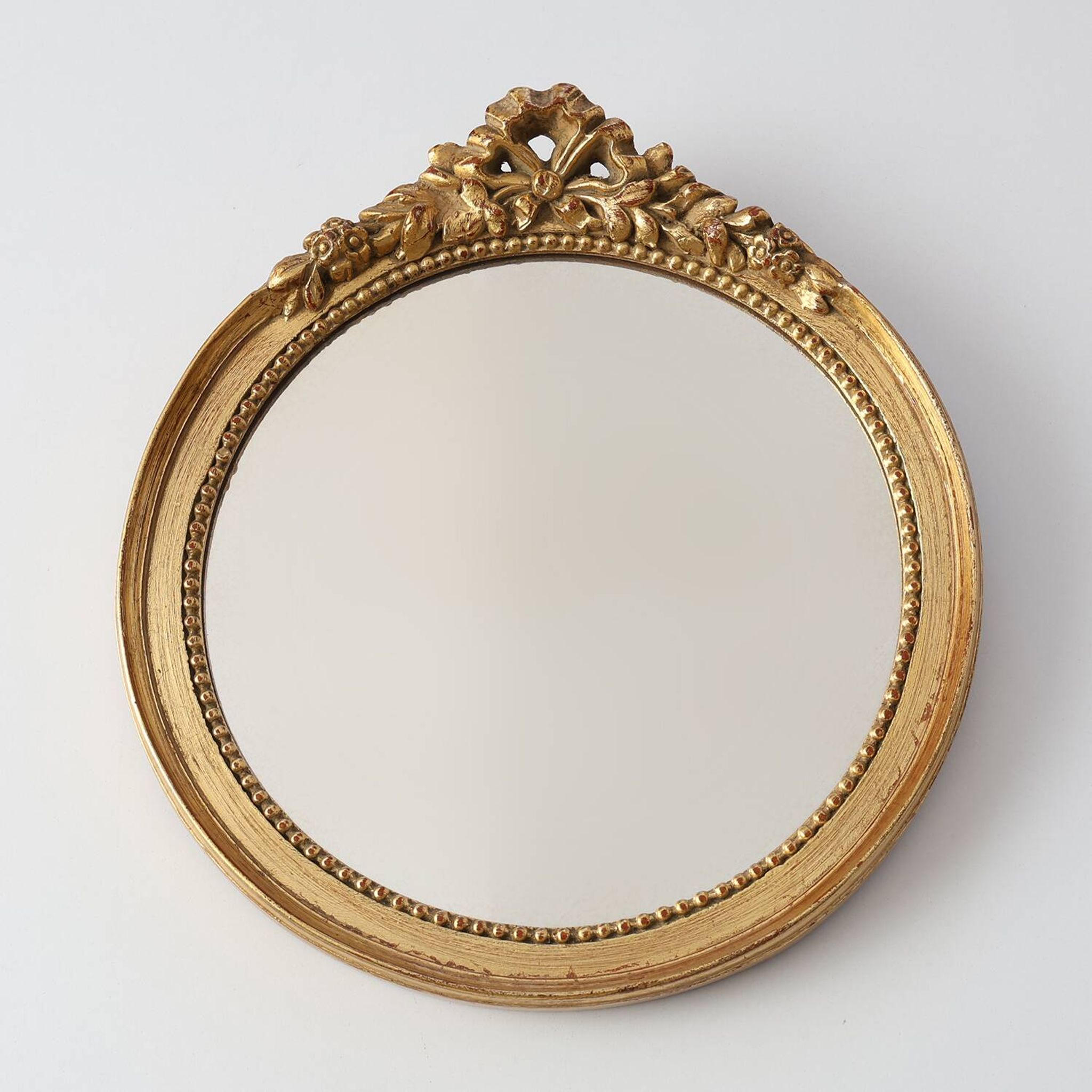 Oval giltwood mirror with rococo-style floral crest, mid-20th century