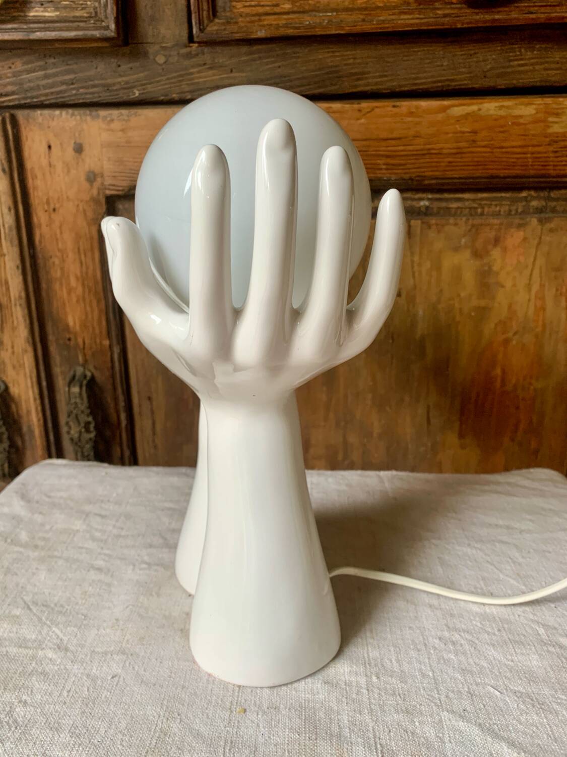 Ceramic table lamp depicting two hands holding a globe, 1980