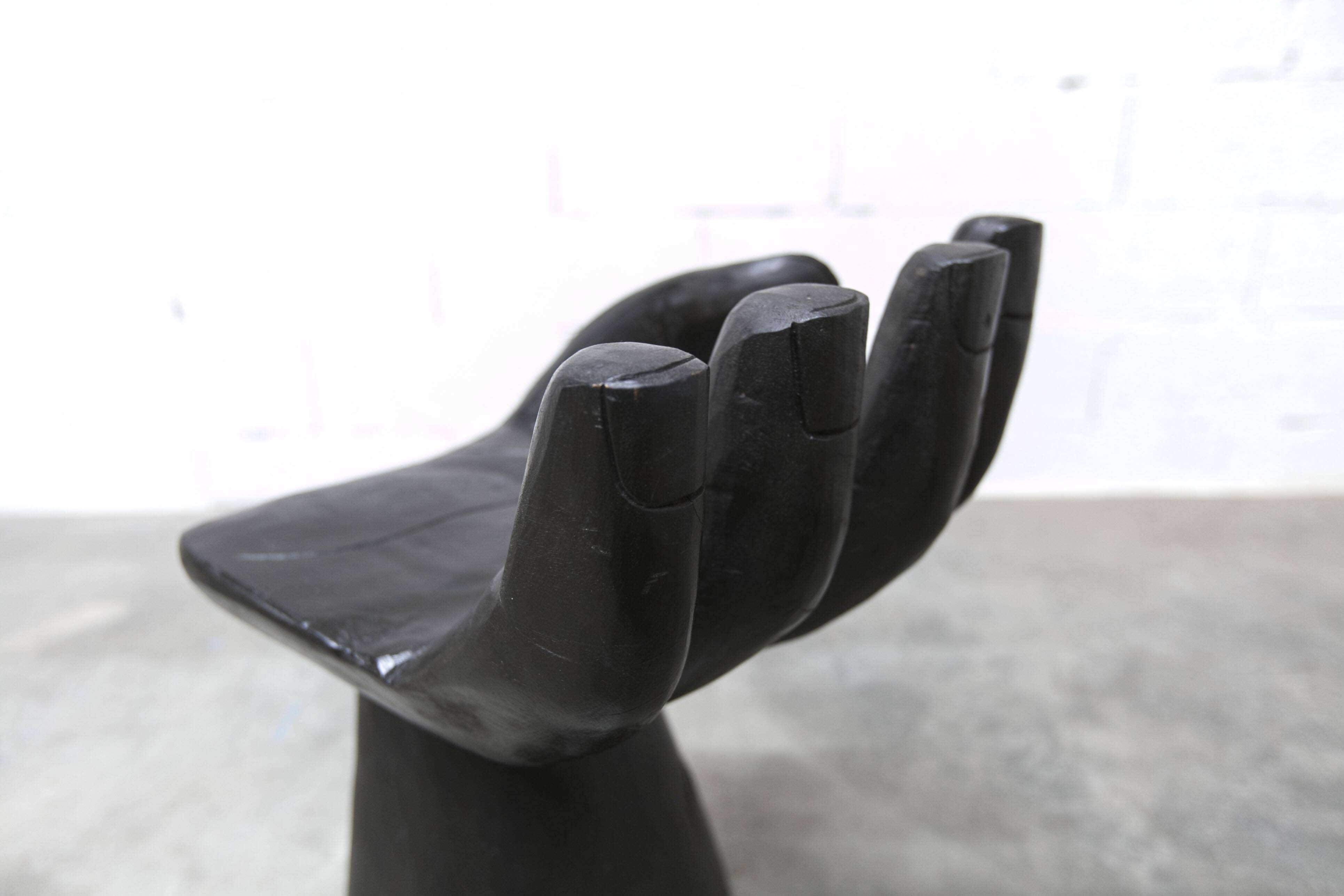 Black armchair chair in carved wood in the shape of a hand