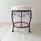 Black iron stool/pouf with its boucle fabric cushion.