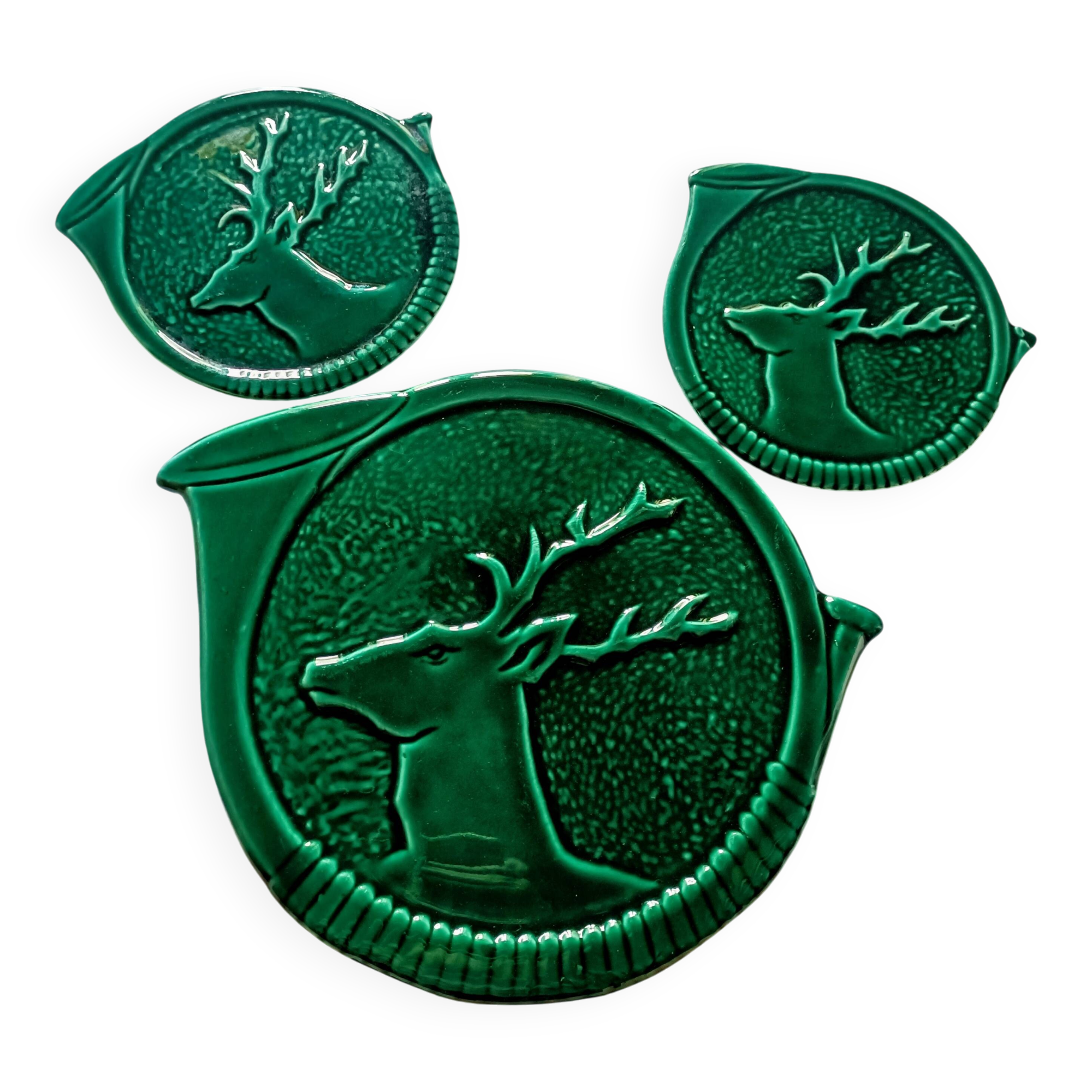 A trivet and two bottle holders in green Vallauris majolica.