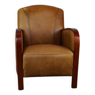Luxurious cowhide Art Deco design armchair with wooden armrests and cognac-colored leather