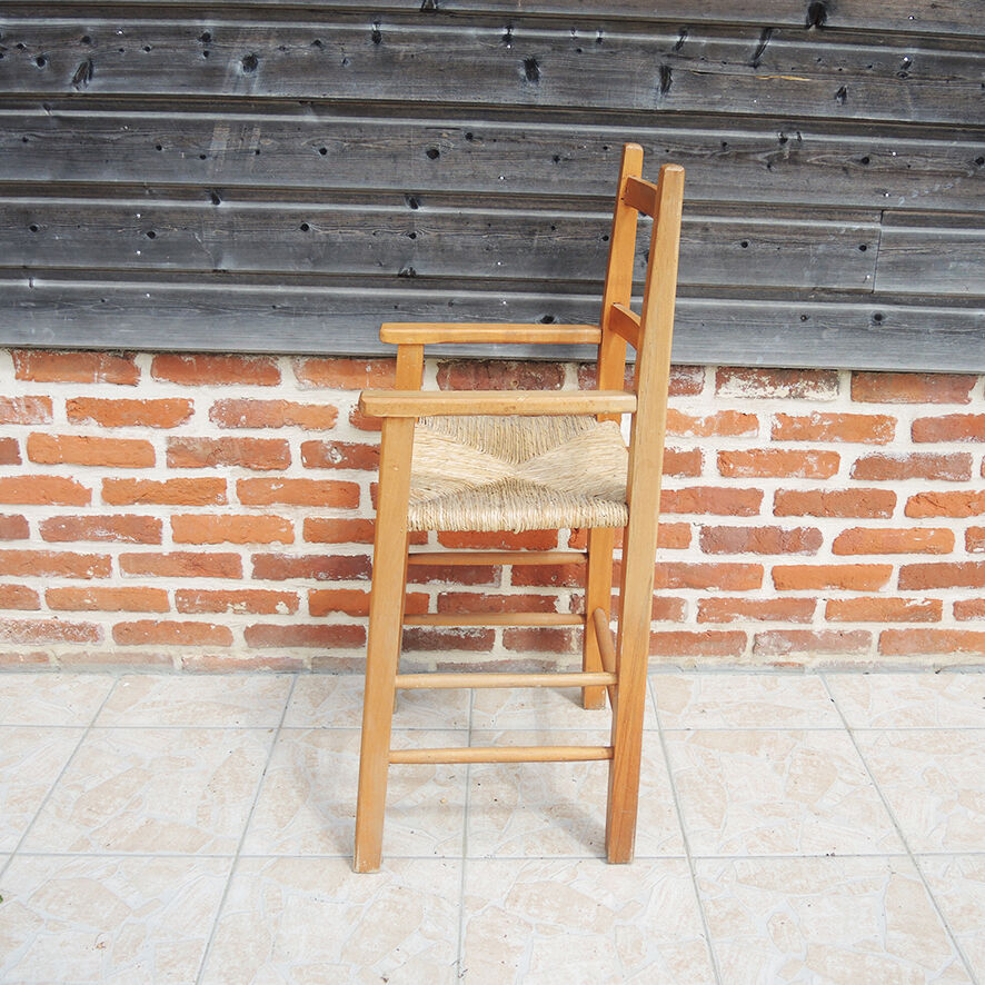Old wooden high chair for children with straw.