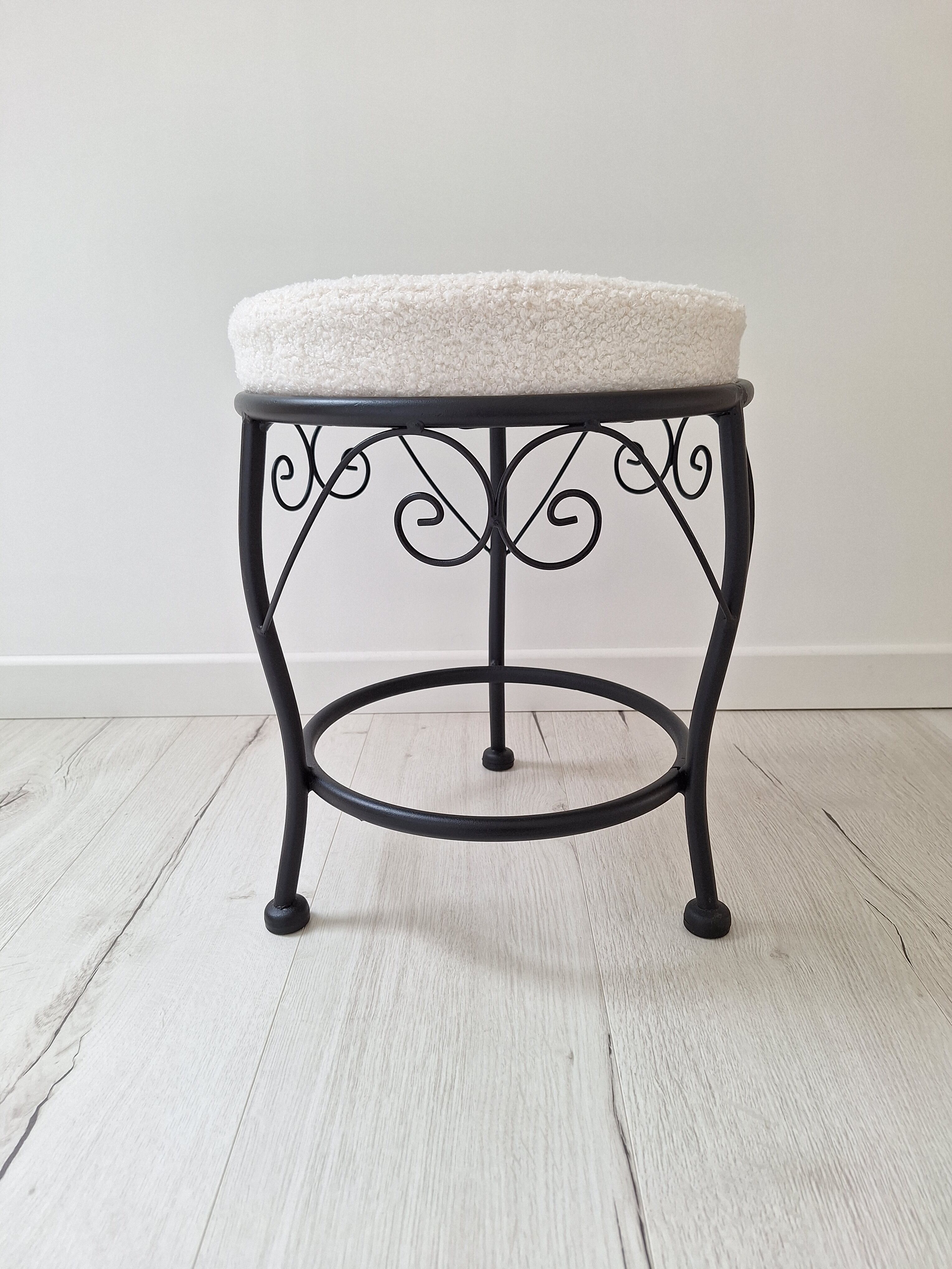Black iron stool/pouf with its boucle fabric cushion.
