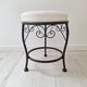 Black iron stool/pouf with its boucle fabric cushion.