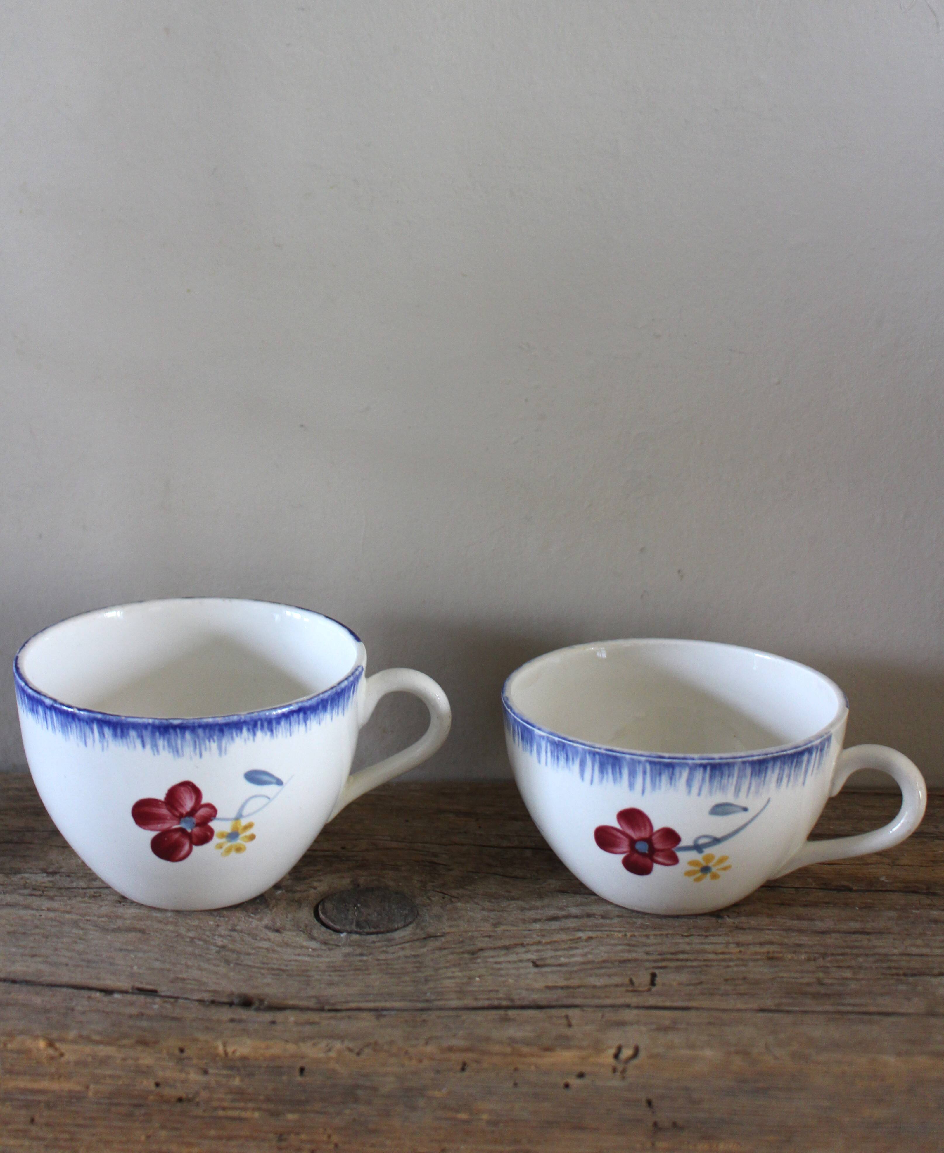 A set of two Digoin earthenware cups with blue, red, and yellow flowers.