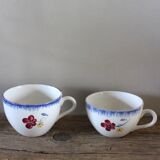 A set of two Digoin earthenware cups with blue, red, and yellow flowers.