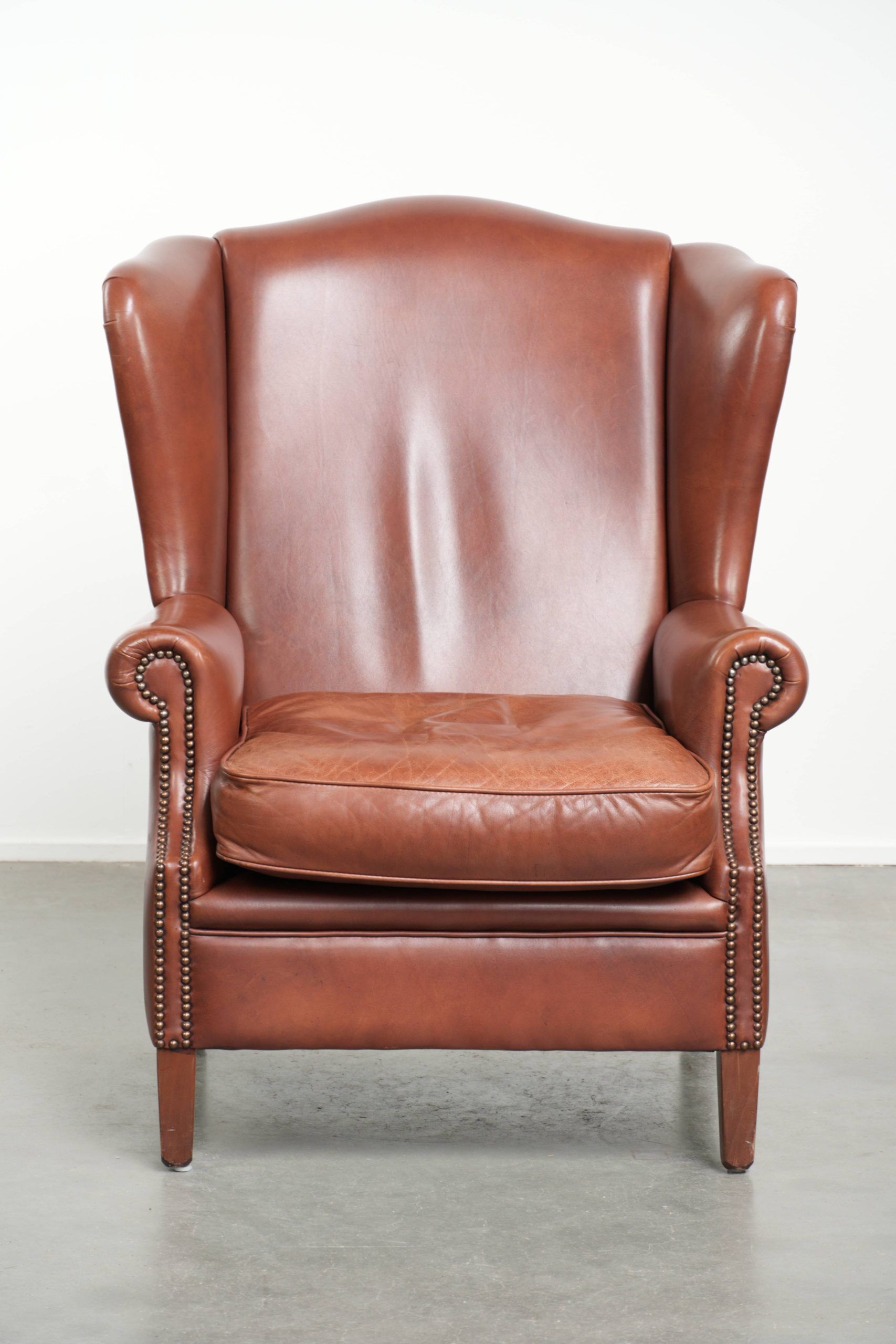 Cognac-coloured cow leather wingback armchair in English style
