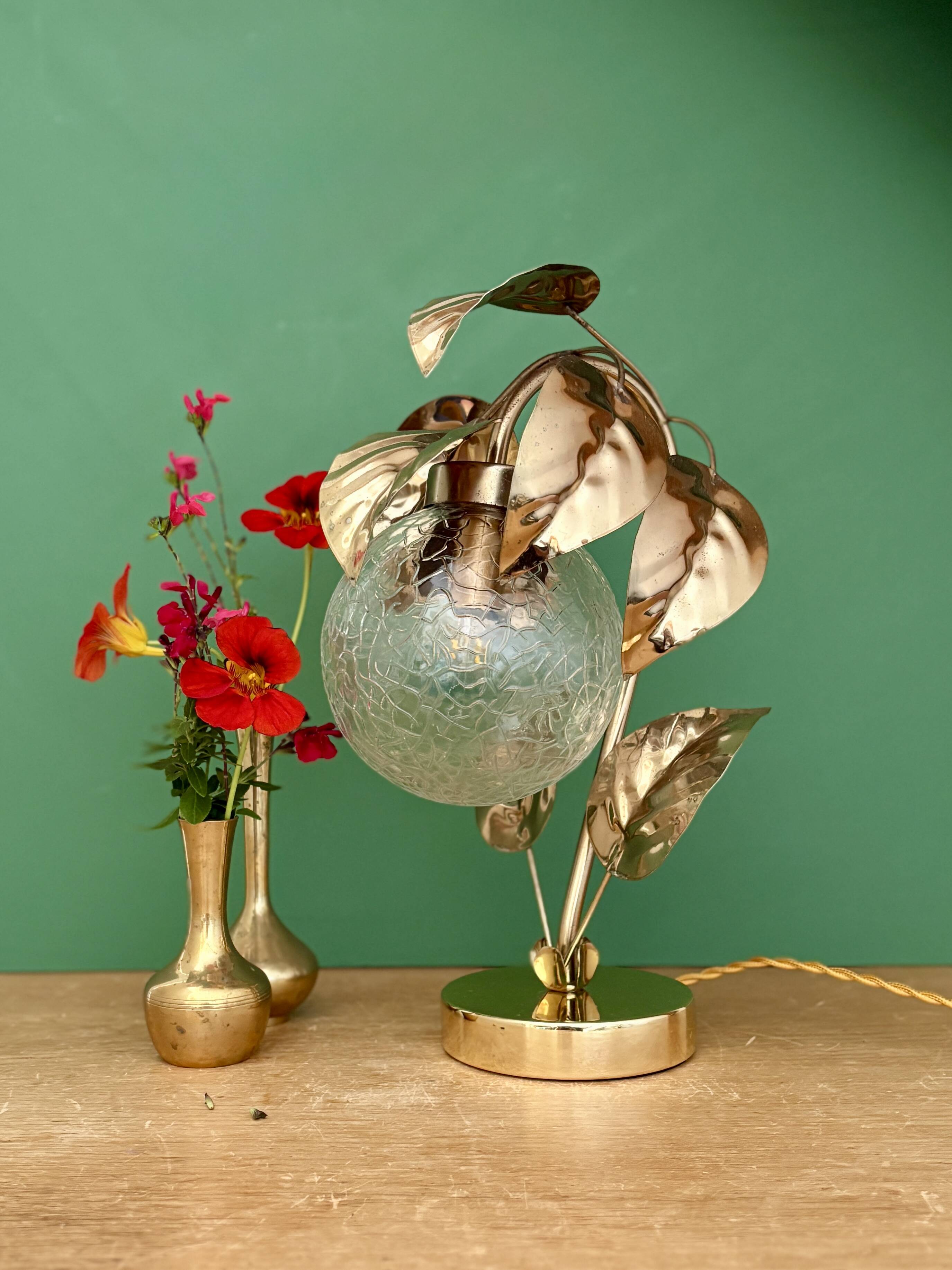 Vintage lamp with brass leaf design and transparent glass globe.