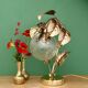 Vintage lamp with brass leaf design and transparent glass globe.