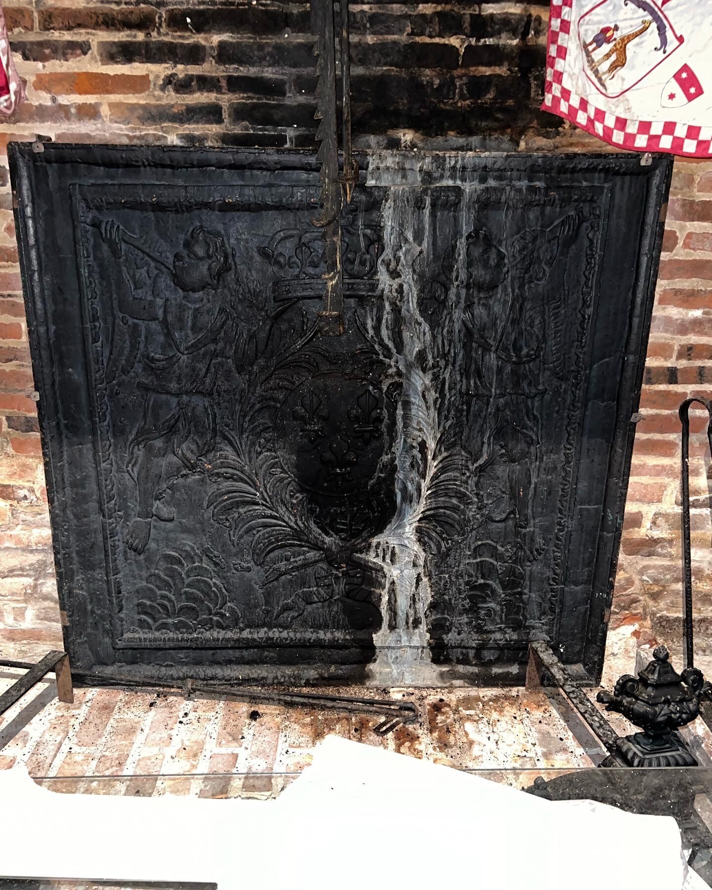 huge old fireplace plate has decoration of angels, crown and fleurs-de-lis