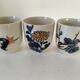 Set of three hand-painted porcelain cups with floral patterns.