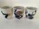 Set of three hand-painted porcelain cups with floral patterns.