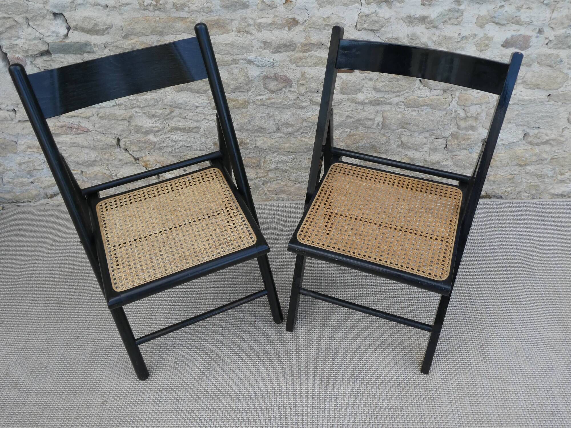 Paire de chaises pliantes en bois noirci et assise cannée