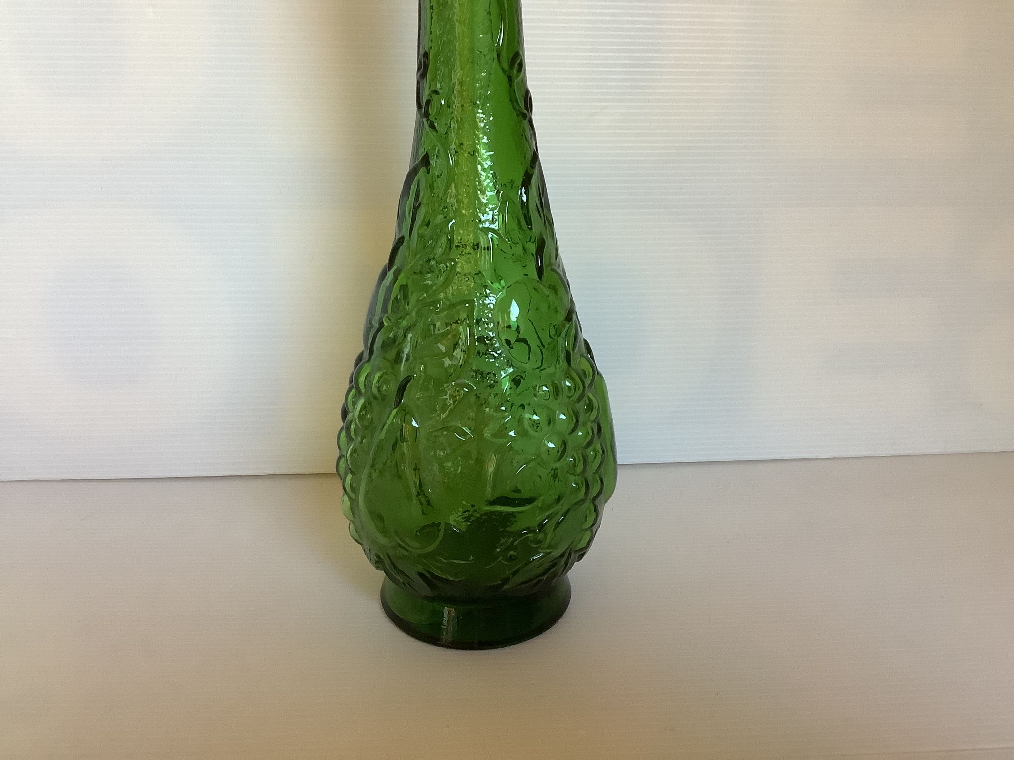 Green carafe bottle with apple, pear, and grape pattern from Italy.