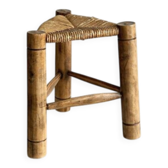 Antique tripod stool in light wood with a woven straw seat.