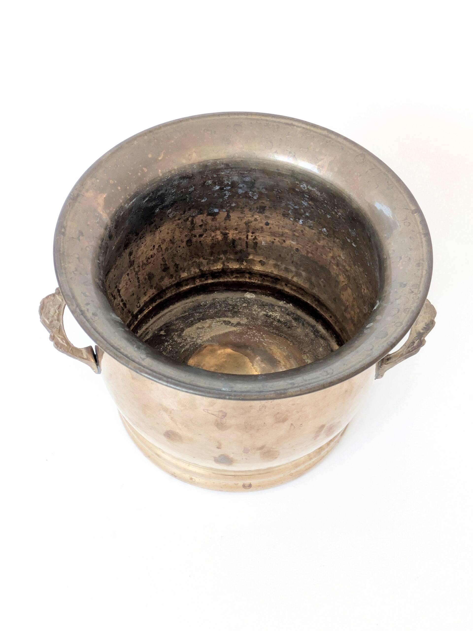 Vintage round cache-pot in hammered brass with decorative handles and patina.