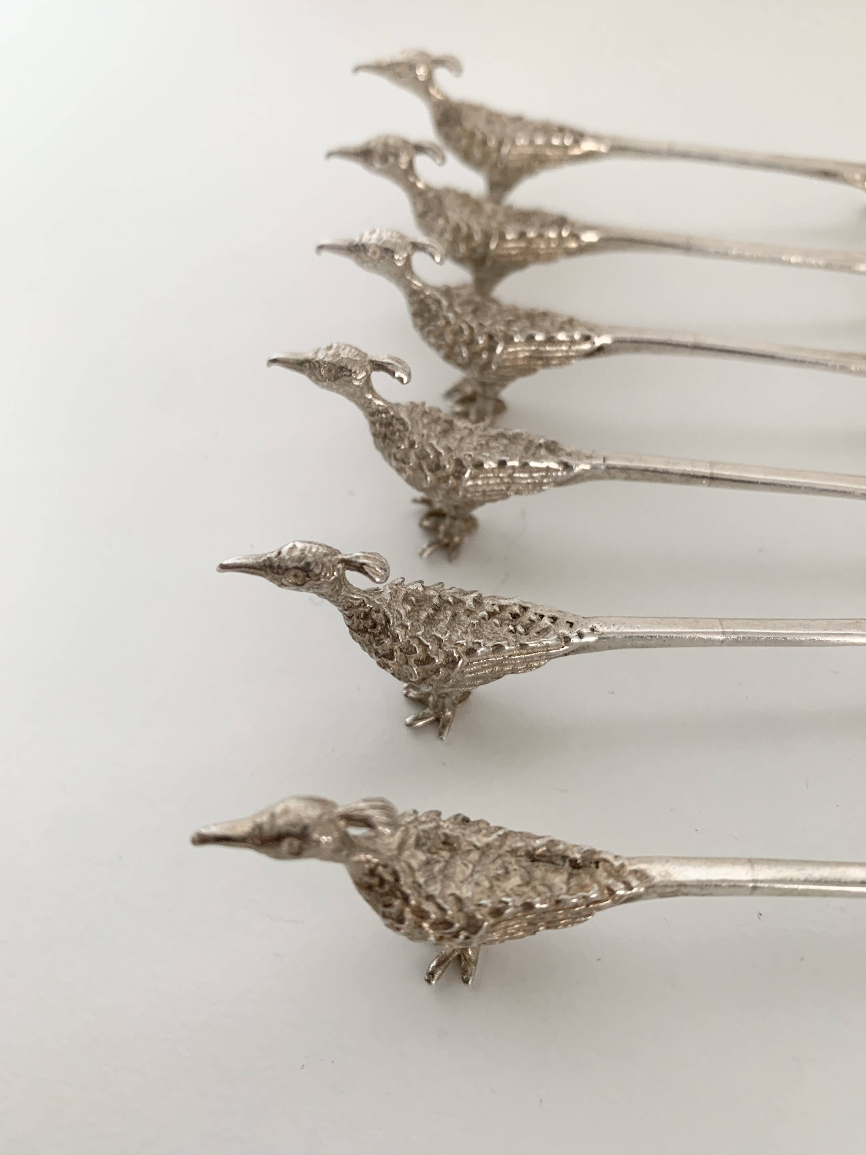 Six silver-plated knife rests in the shape of peacocks.