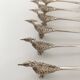 Six silver-plated knife rests in the shape of peacocks.