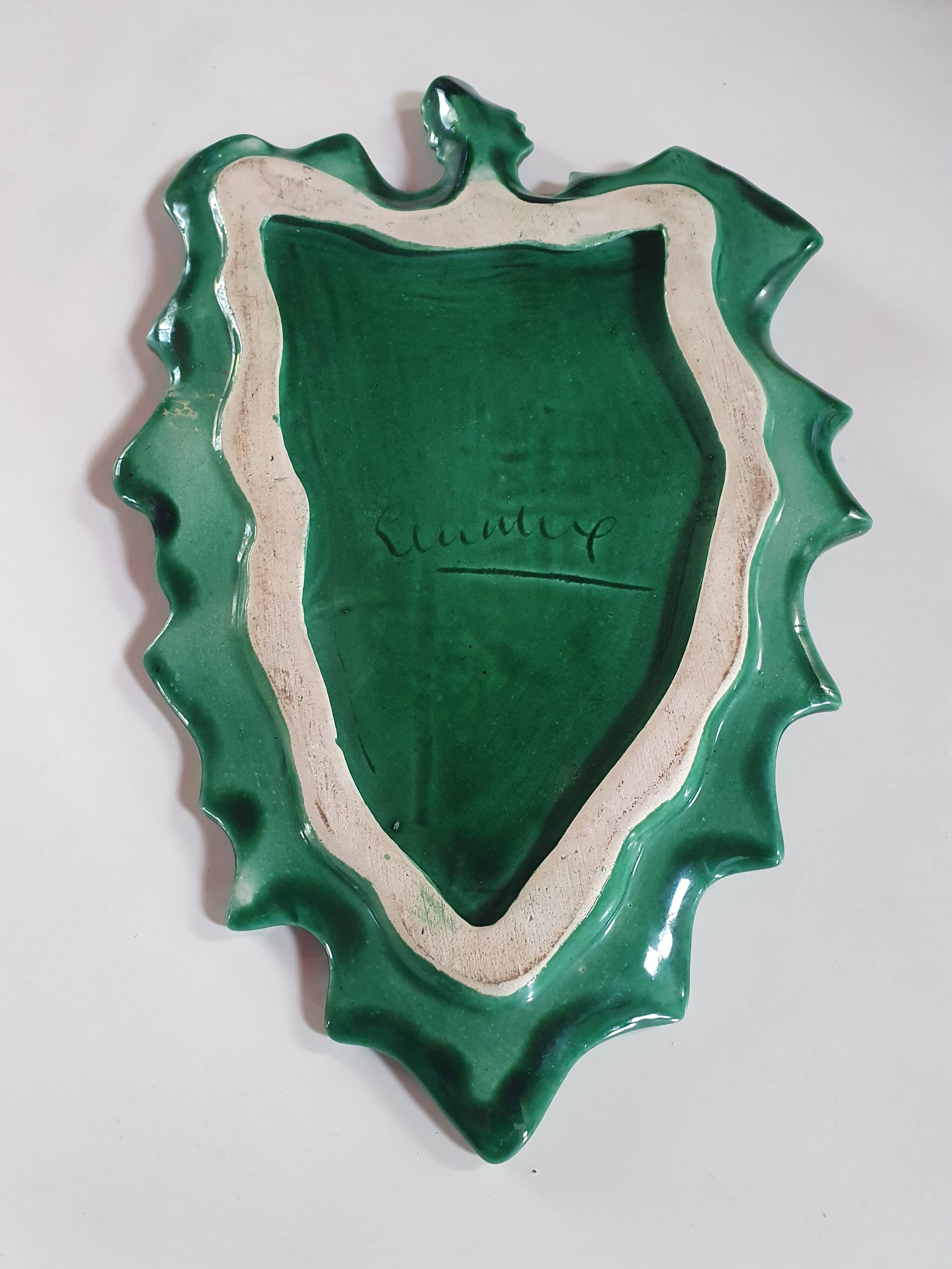 empty green ceramic pocket cup, small chips on the edges, signed