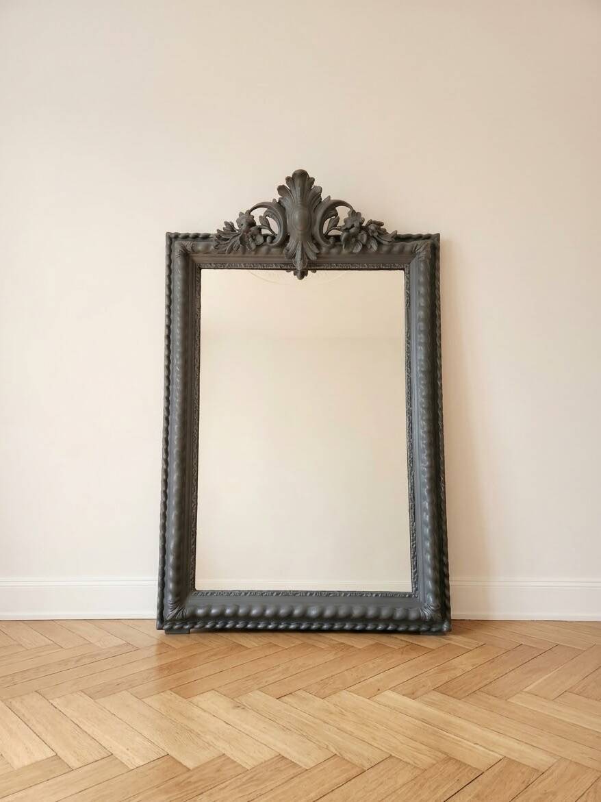 Antique mirror with a sculpted pediment in classic grey style.