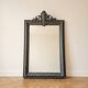 Antique mirror with a sculpted pediment in classic grey style.