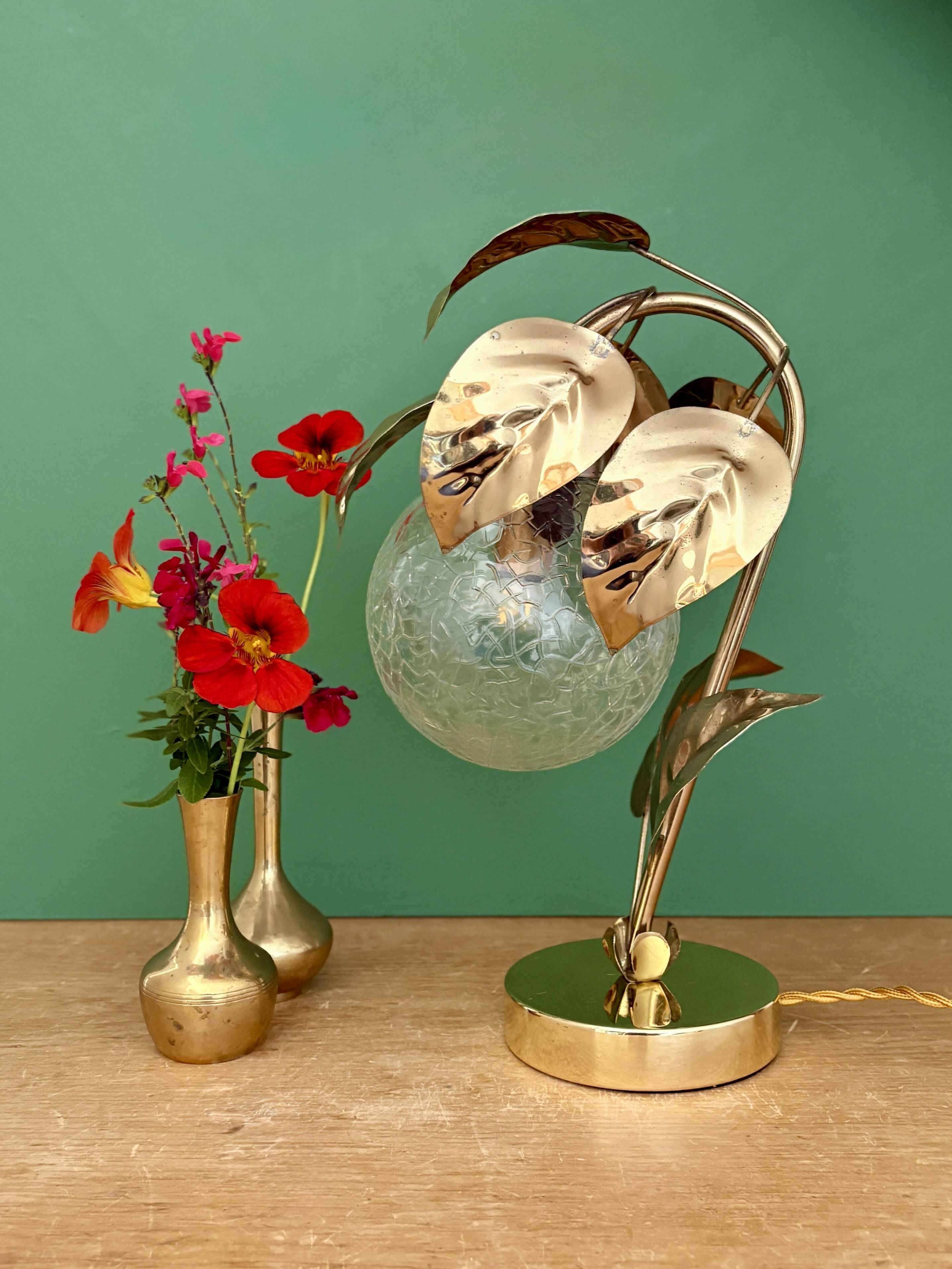 Vintage lamp with brass leaf design and transparent glass globe.
