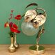 Vintage lamp with brass leaf design and transparent glass globe.