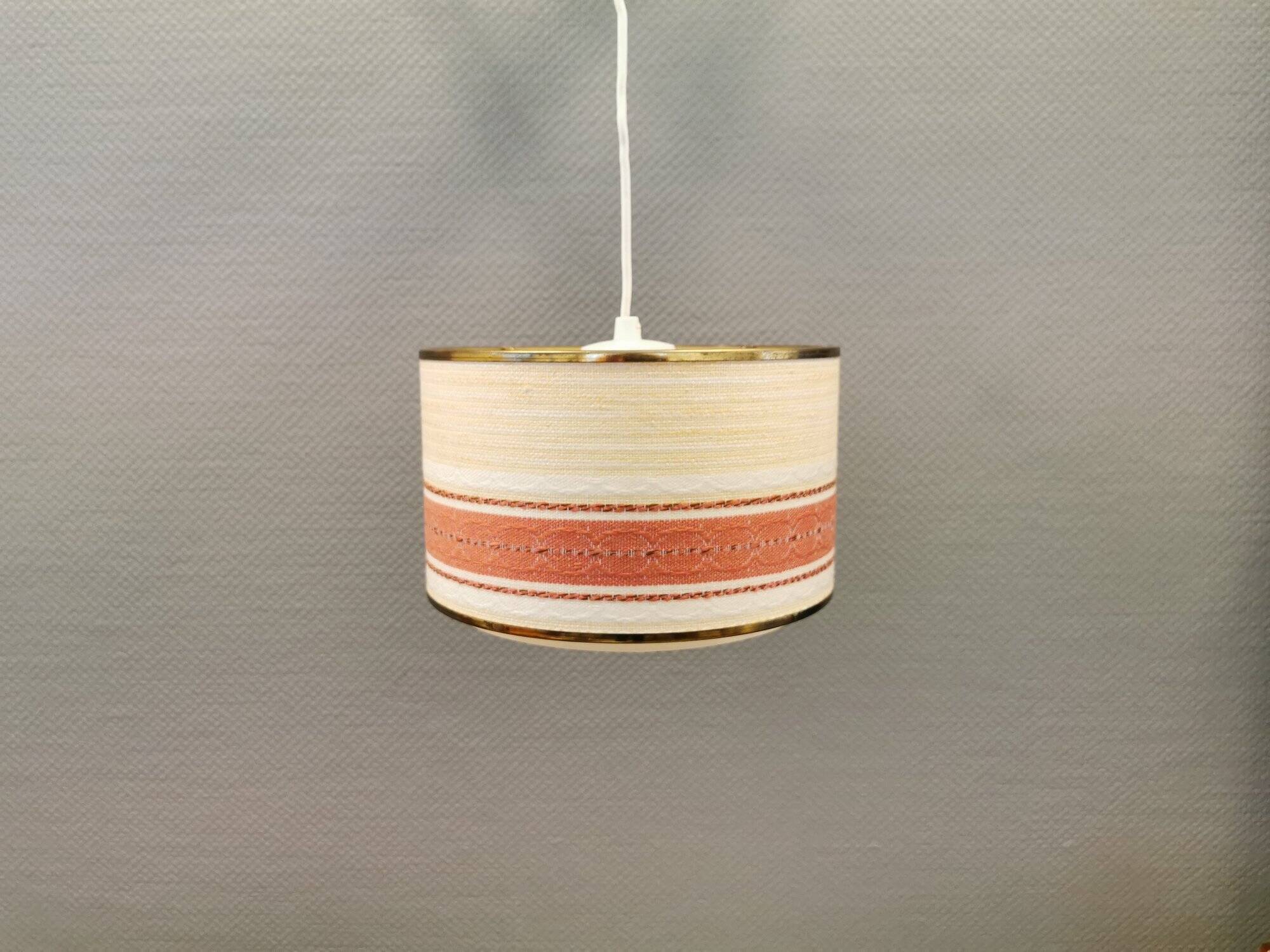 Hanging lamp with brass-coloured details, made of fabric with intact plastic bottom grille.