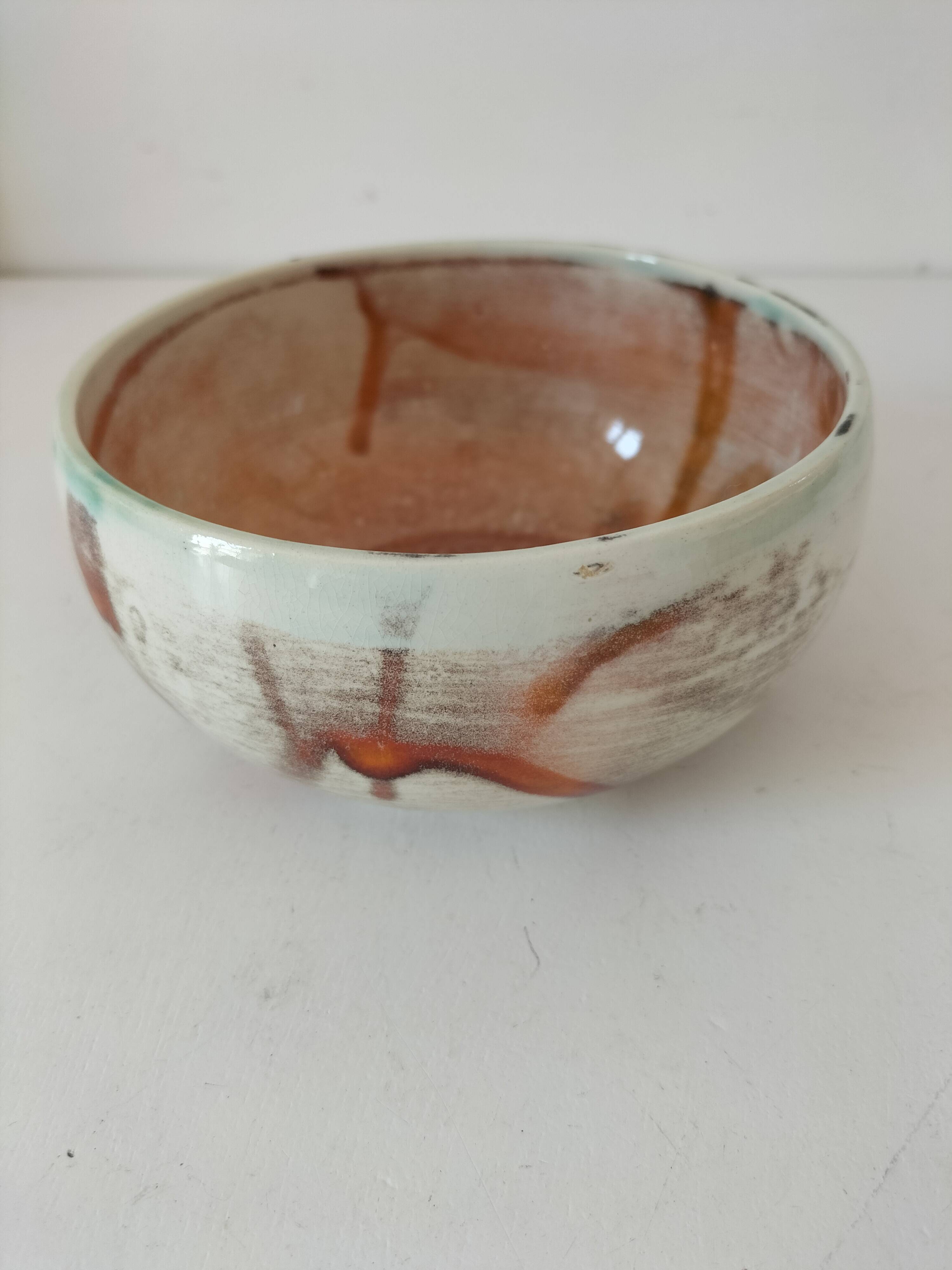 Red-orange glazed ceramic workshop bowl with floral decoration.