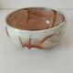 Red-orange glazed ceramic workshop bowl with floral decoration.