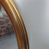 Large and elegant oval gilded mirror with its beveled glass