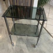 Serving dessert trolley with 2 smoked glass shelves and metal structure.
