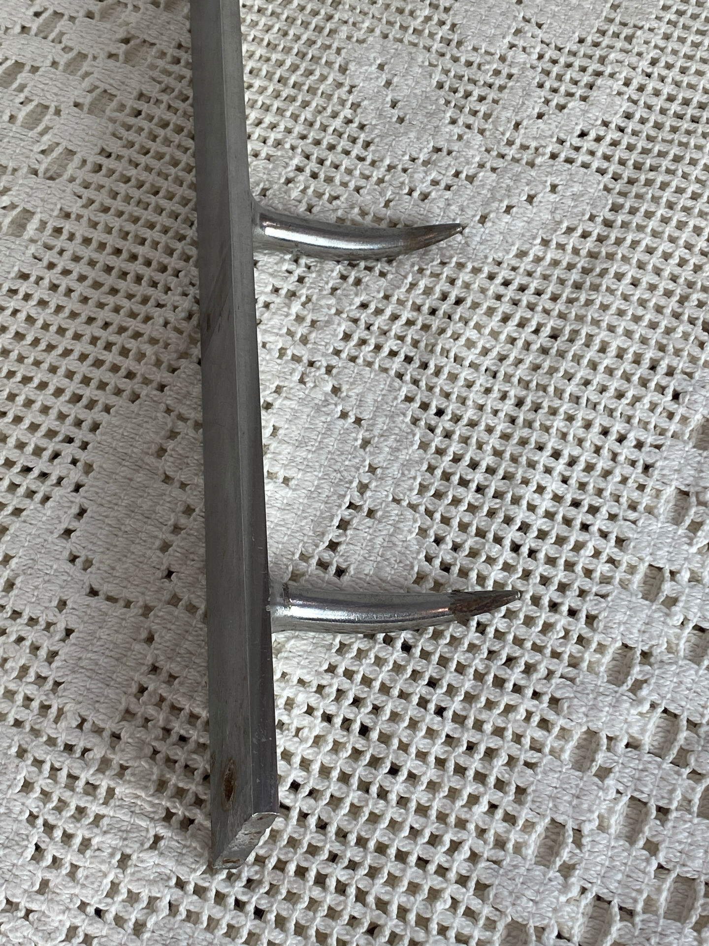 Stainless steel butcher's hook, known as a "wolf tooth bar."